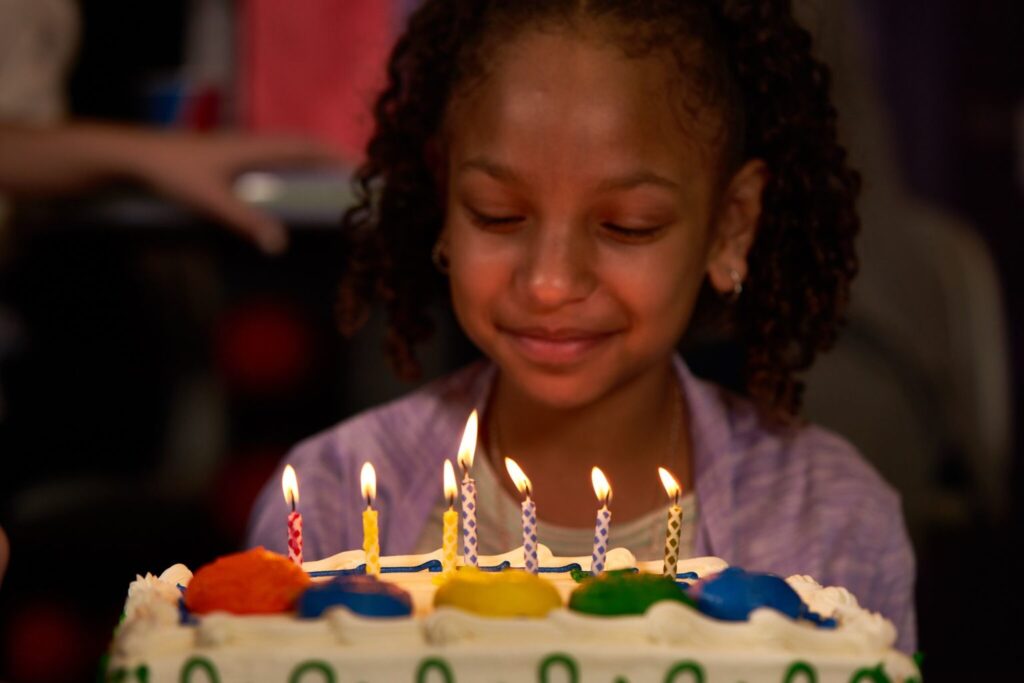kid at a birthday party in front of a birthday cake