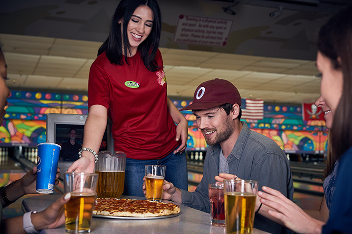 Pin Chasers employee serving pizza to happy customers
