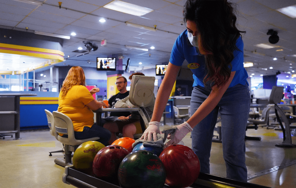 Pin Chasers employee sanitizing bowling balls