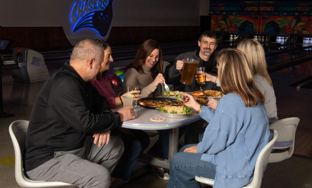 Family sharing pizza and drinks at their bowling lane